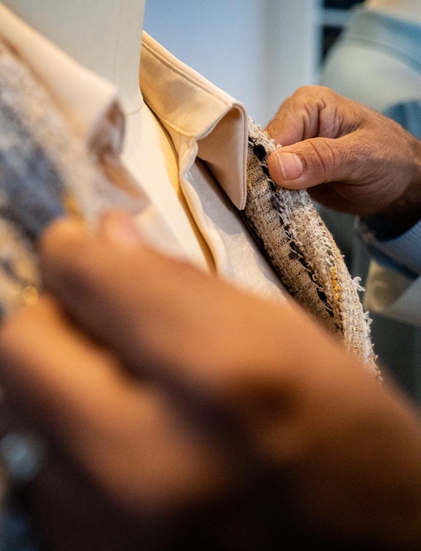 Hand-finishing the lapel of a cream jacket with tweed trim