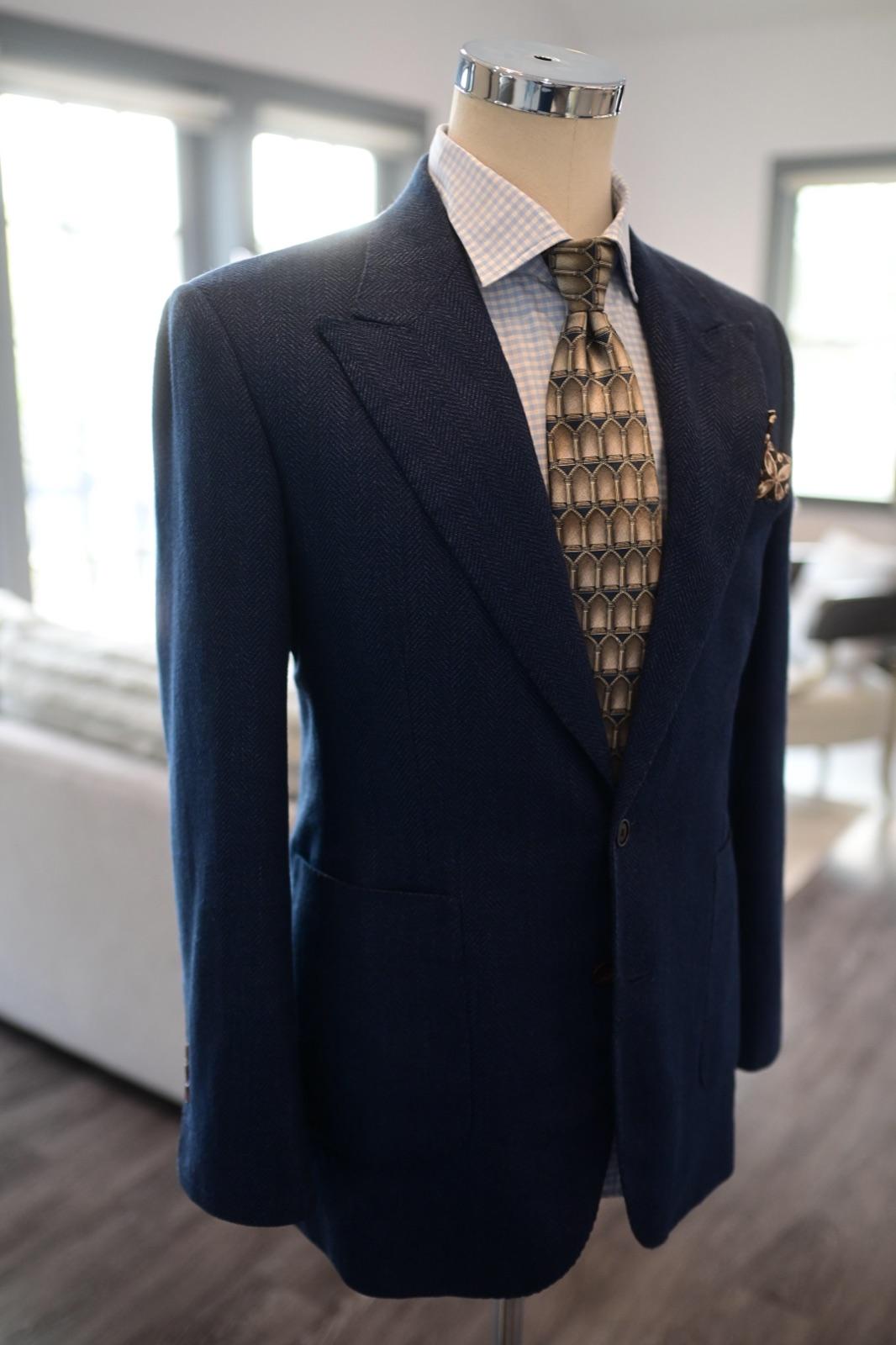 Navy herringbone blazer on dress form with patterned tie, check shirt, and gold pocket square